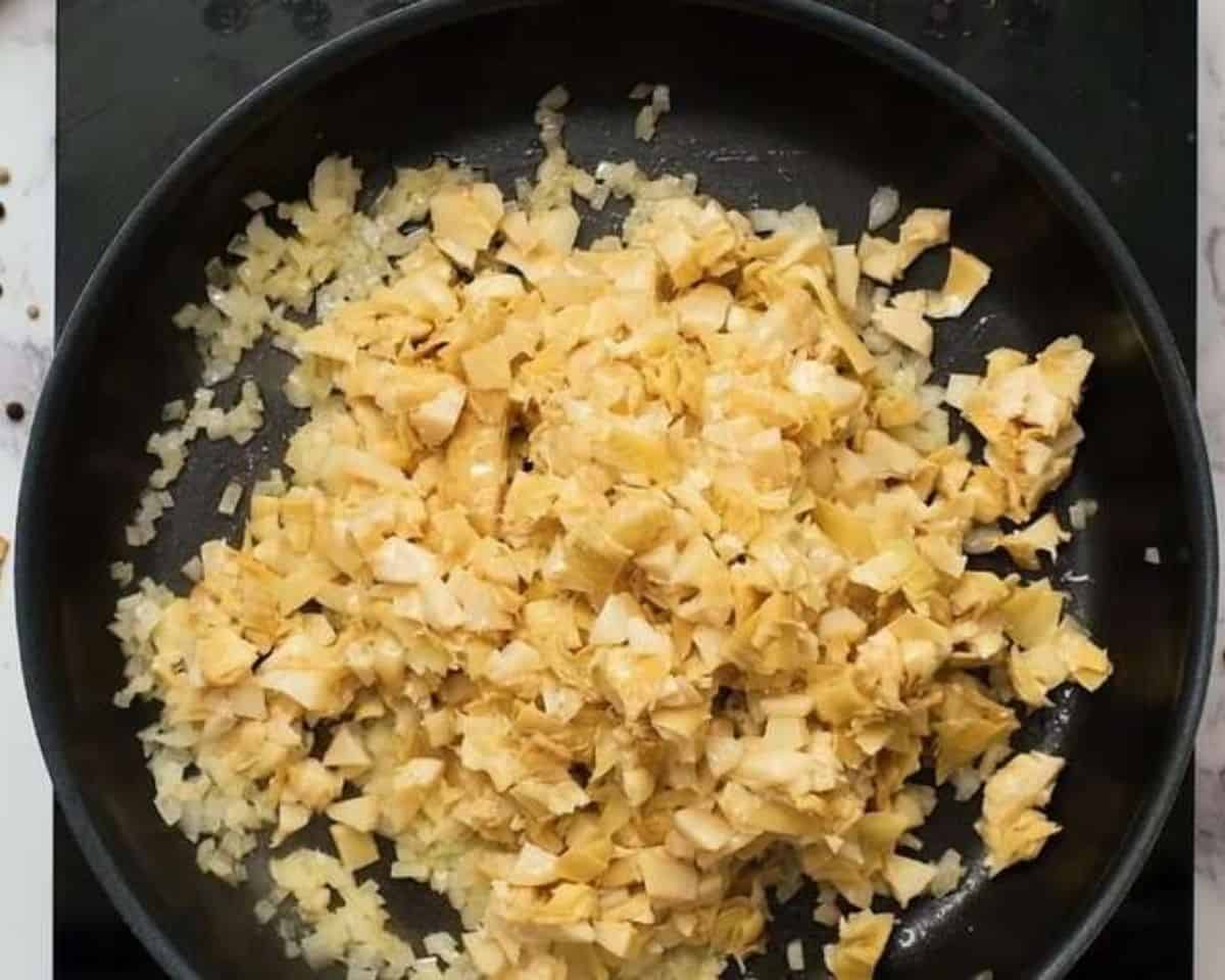 Cooking spinach and artichokes in a skillet.