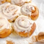 cinnamon rolls with icing and cinnamon on a baking sheet.
