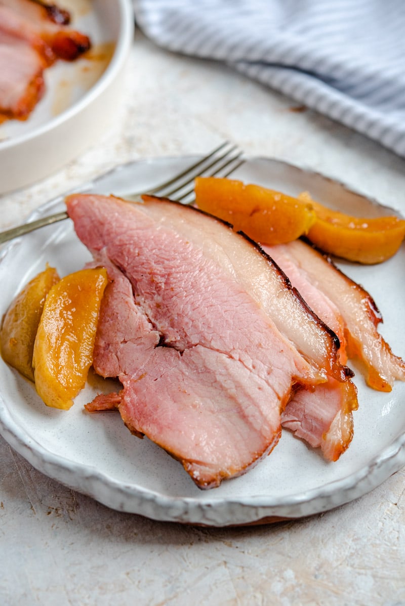 Slices of glazed ham on a plate with apples