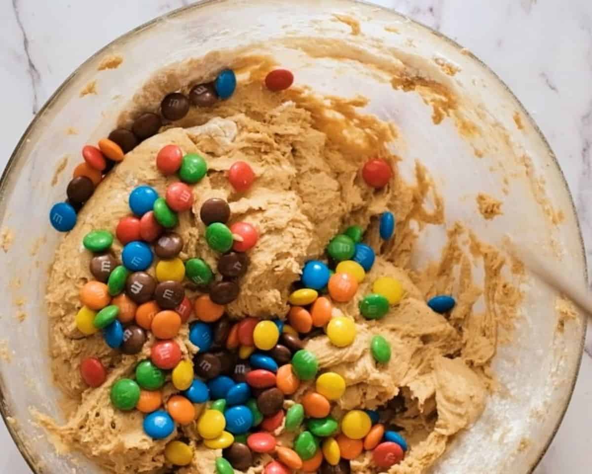 Adding M&Ms to the batter.
