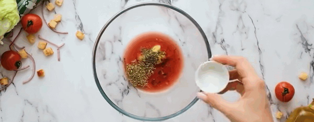 Combining the ingredients to make the salad dressing in a glass bowl. 