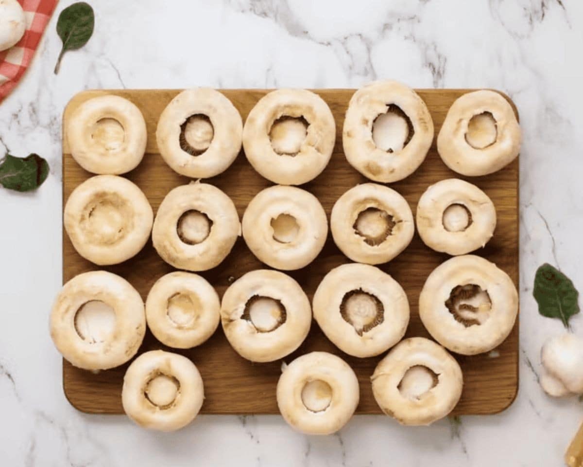 Mushrooms with the stems removed on a cutting board.