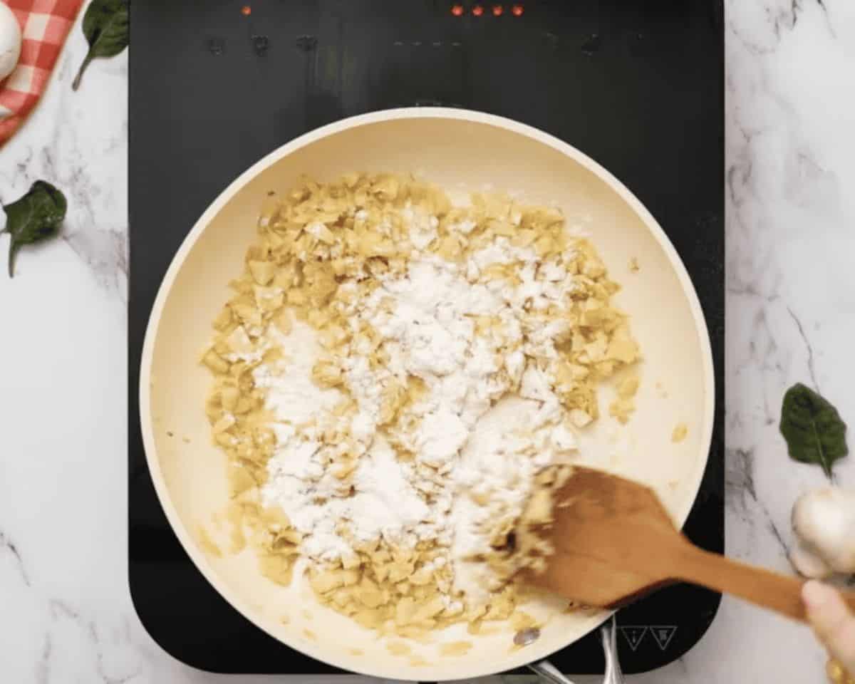 Adding flour to the vegetable mixture.