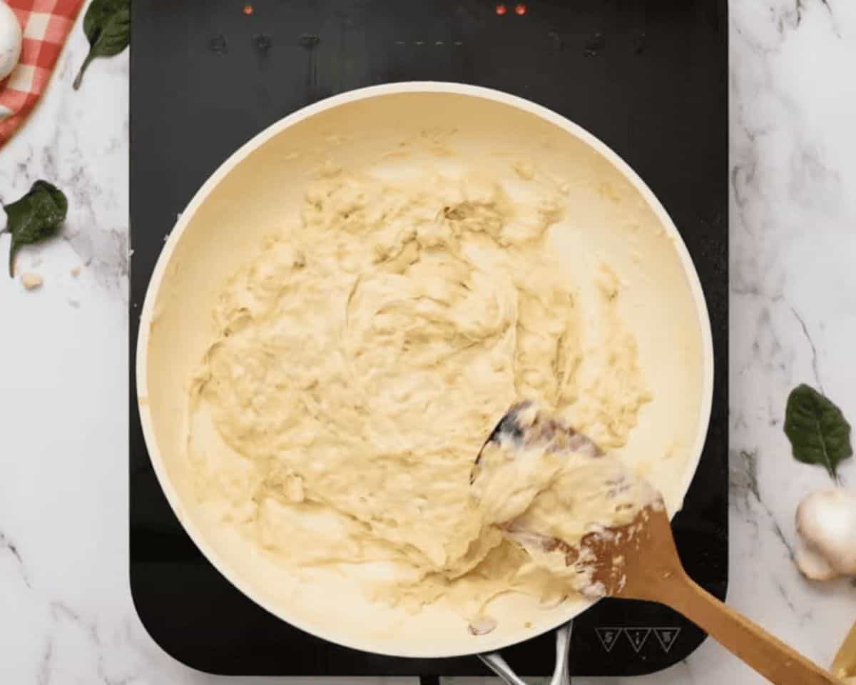 Adding cream and seasonings to the mixture.