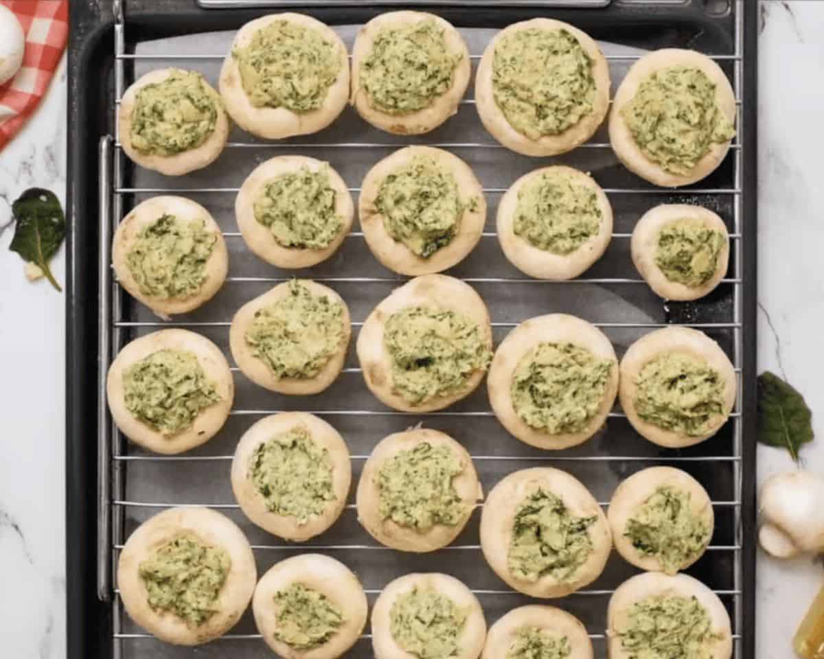 Stuffed mushrooms on a wire rack inside the baking pan.