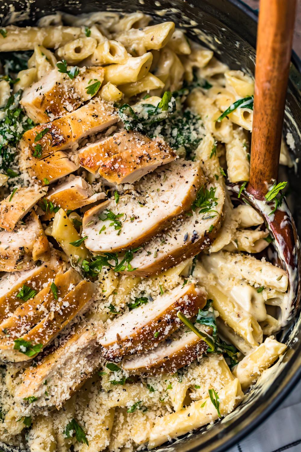 close up photo of creamy penne ziti pasta with sliced chicken on the top