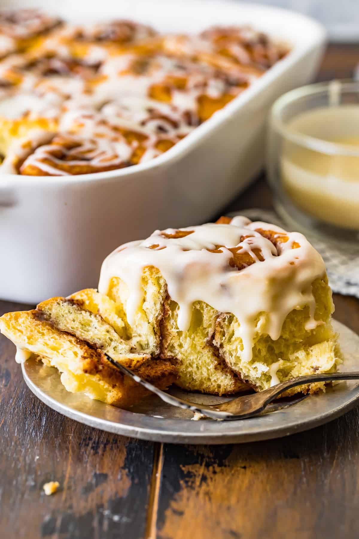 A cinnamon roll on a plate cut with a fork