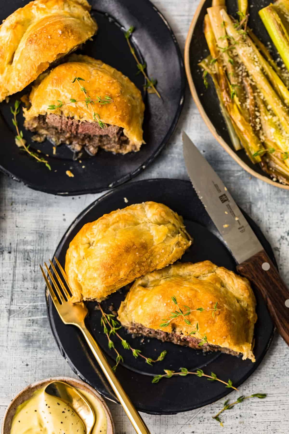 Beef wellingtons served on two black plates
