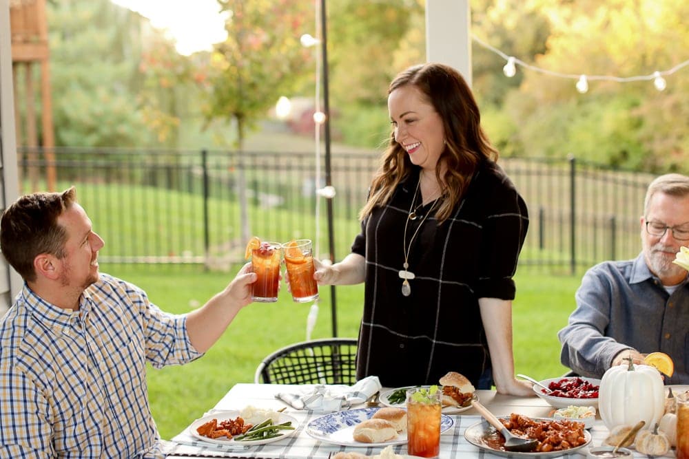 A couple at a dinner table clanking their drinks together