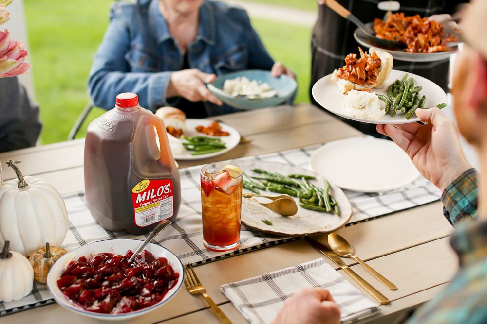 Milos Sweet Tea sitting on a table with food being passed around