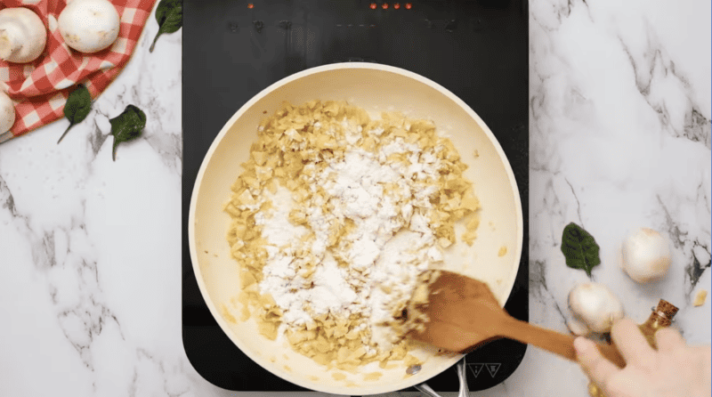 flour sprinkled over chopped artichokes in a pan.