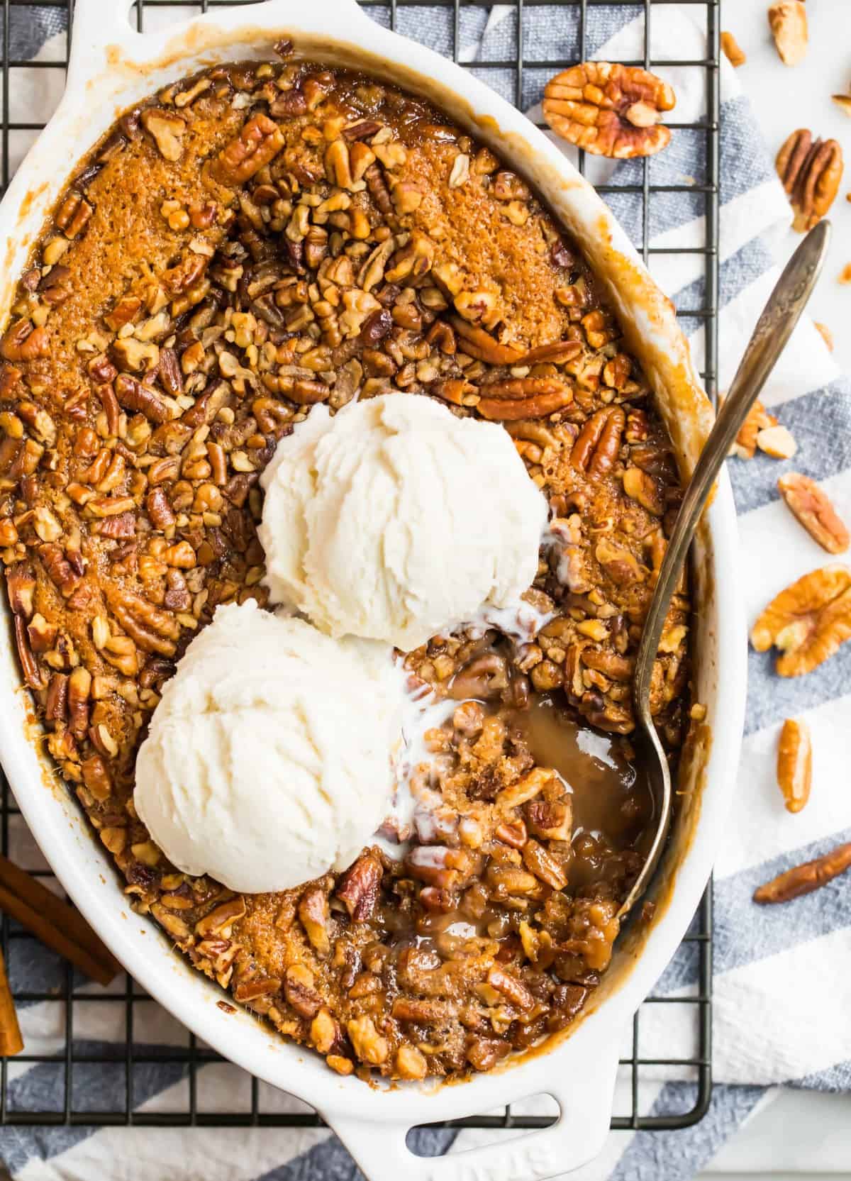 peacan pie cobbler in white baking dish topped with ice cream