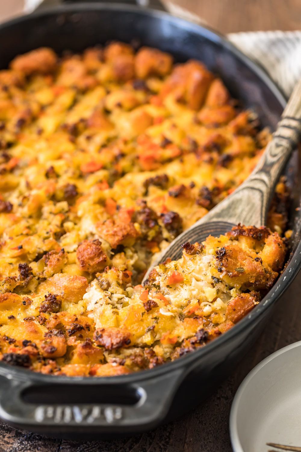 A wooden spoon serving the stuffing from the dish