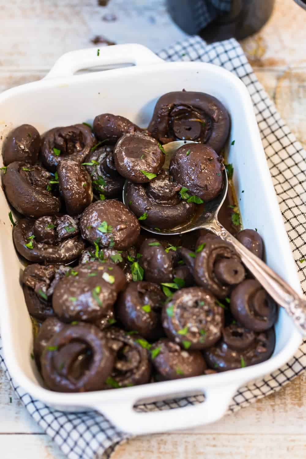 Burgundy mushrooms in a white serving dish with a spoon