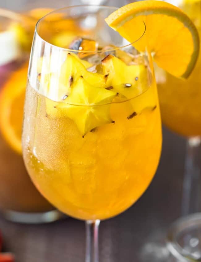 honey bourbon sangria in a wine glass with a sliced orange on the rim