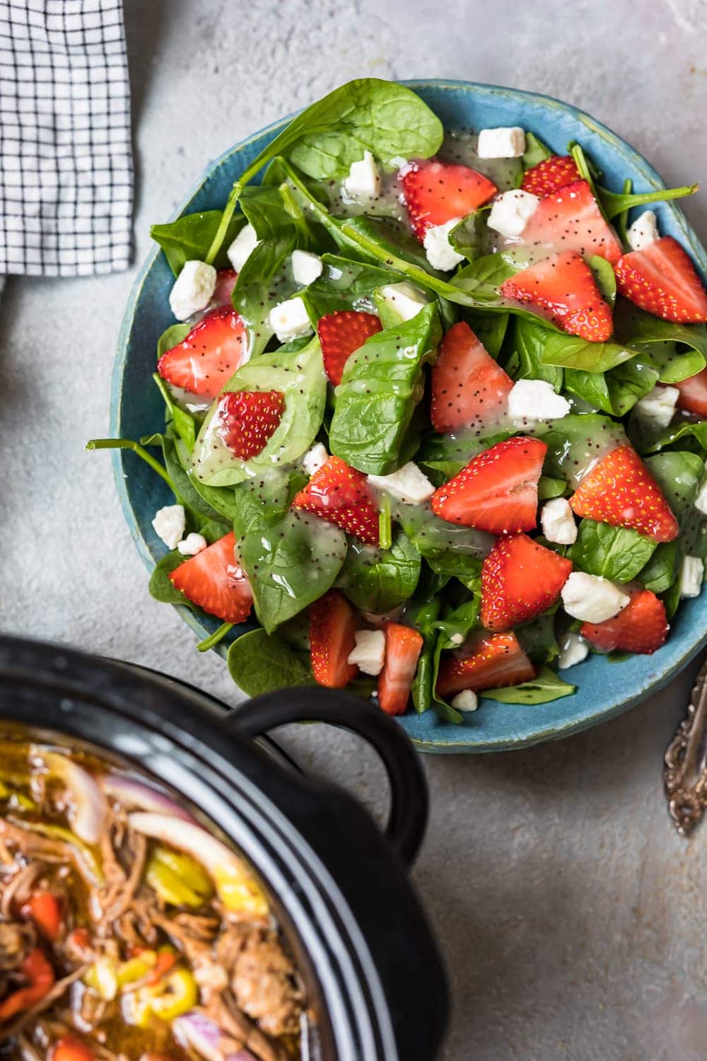 a plate of salad with strawberries and feta cheese