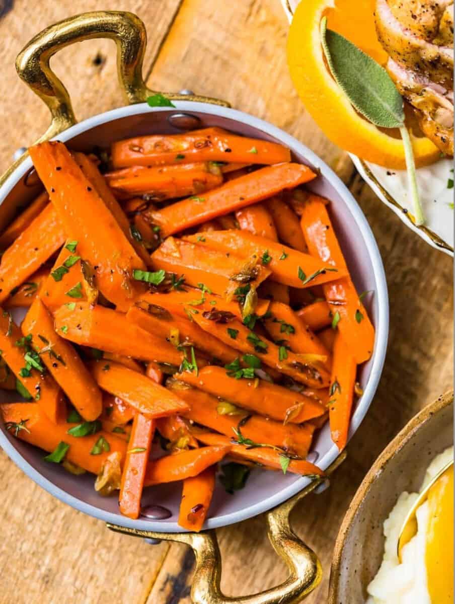 Roasted and sauteed carrots on a wooden table.