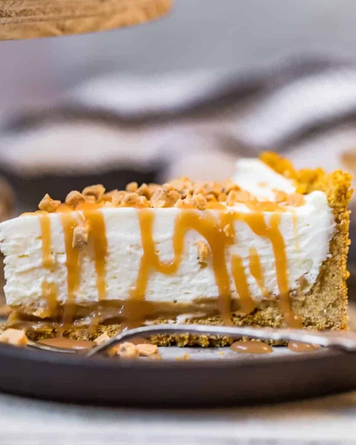 A slice of salted caramel cheesecake on a plate with a fork.
