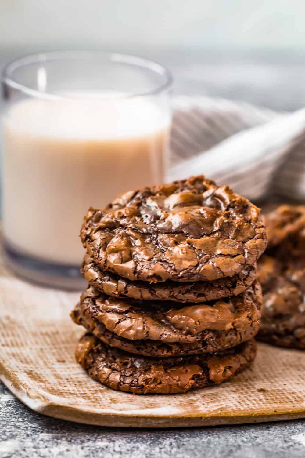 a stack of cookies on a plate in front of a glass of milk