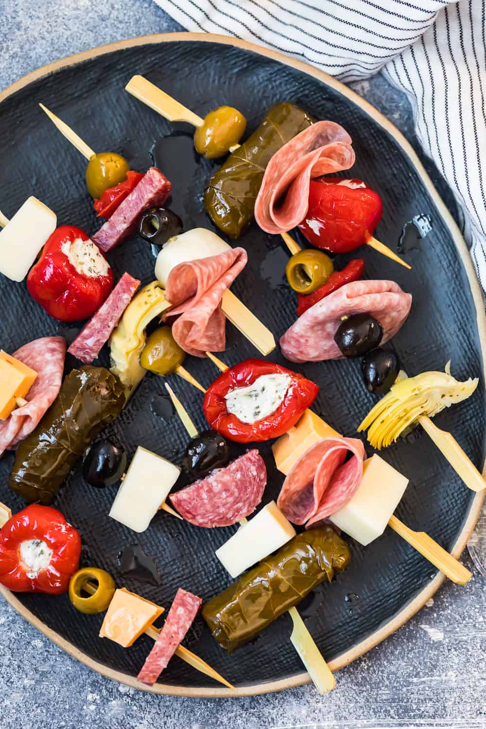 several antipasti skewers on a black plate