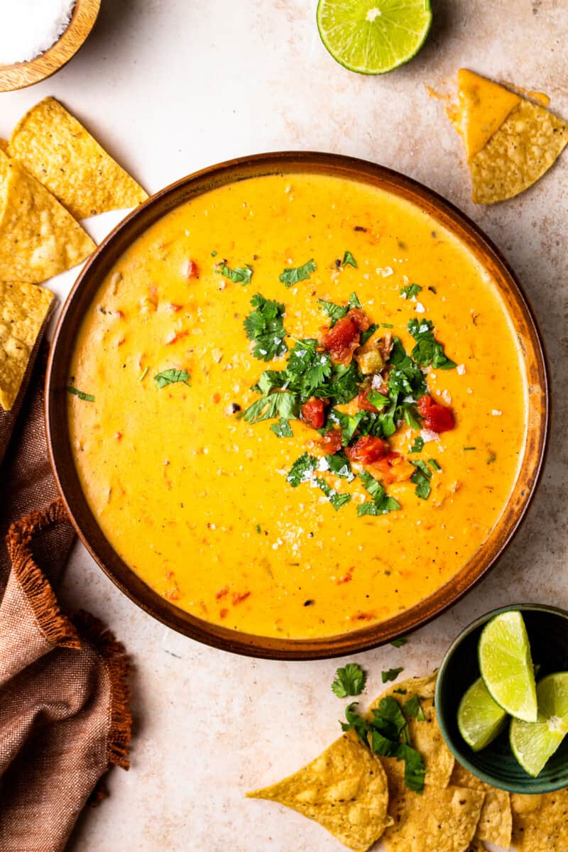 bowl of crockpot queso garnished with tomatoes and cilantro