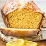 A slice of iced lemon loaf cake on a cutting board.