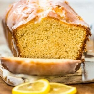 A slice of iced lemon loaf cake on a cutting board.