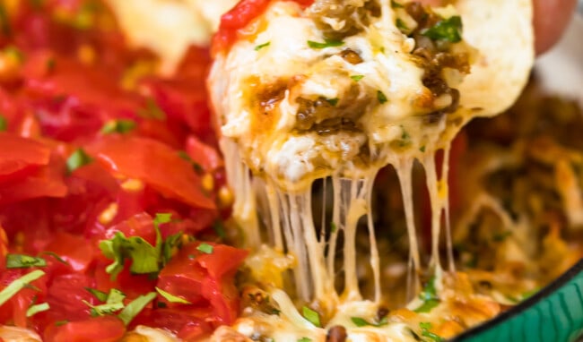 queso fundido in green dish with chip scooping dip