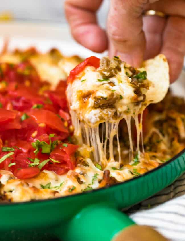 queso fundido in green dish with chip scooping dip