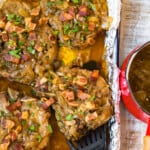 slow cooker smothered pork chops in a pan with a spatula lifting one out