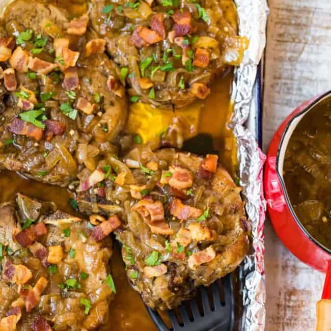 slow cooker smothered pork chops in a pan with a spatula lifting one out
