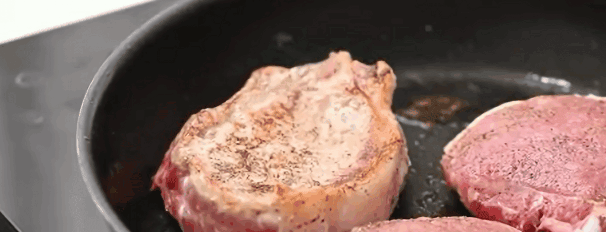 Cooking the pork chops in the pan with the bacon fat. 