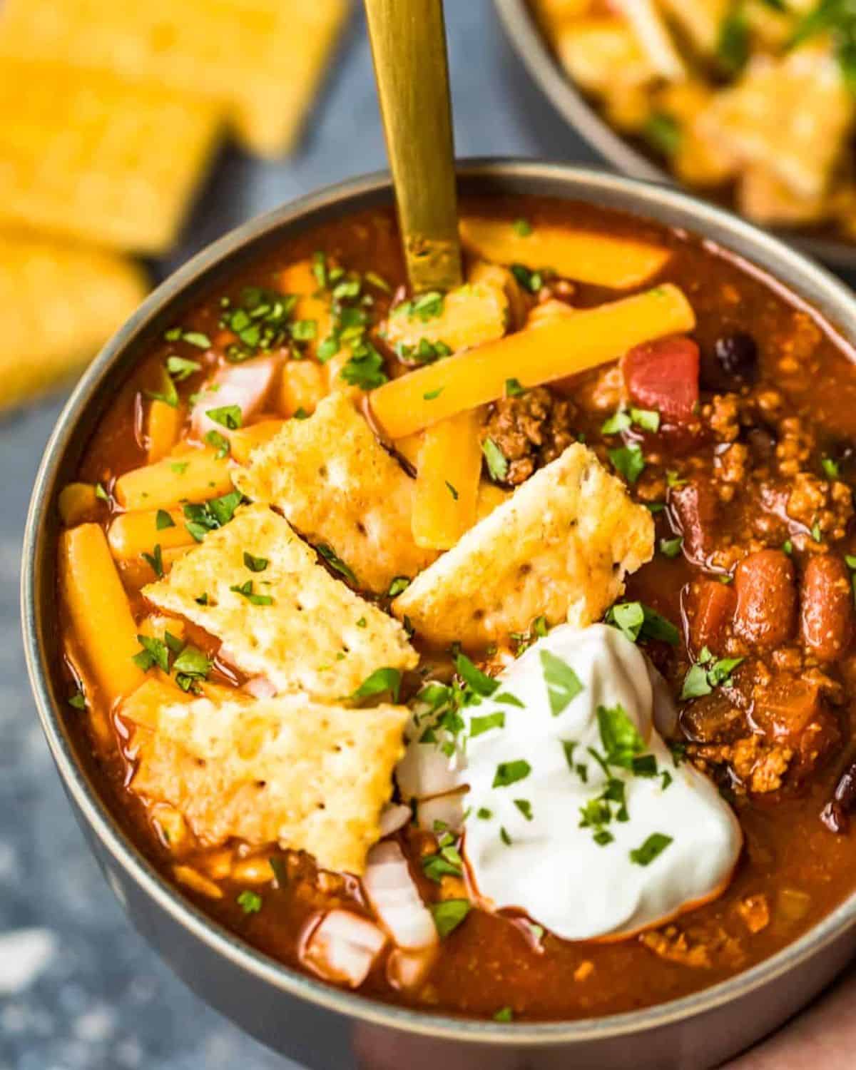 Bowl of chili with cheese, crackers and sour cream.