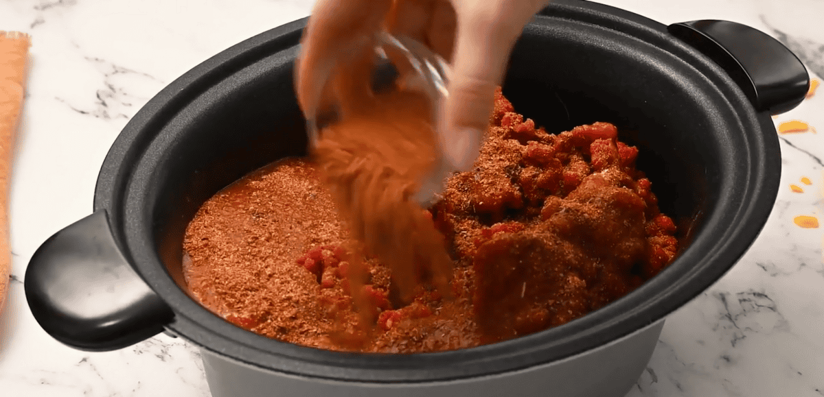 Ingredients to make crock pot taco meat being added to a crockpot. 