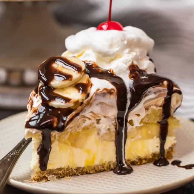 a slice of banana split cake on a plate drizzled in chocolate syrup