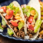 A plate of tacos with crockpot taco meat and vegetables.