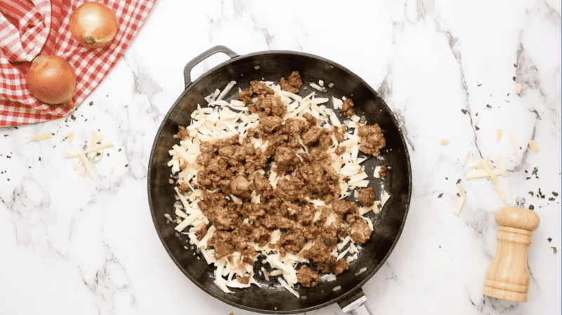 Queso Fundido Recipe: A frying pan with meat, onions and cheese.