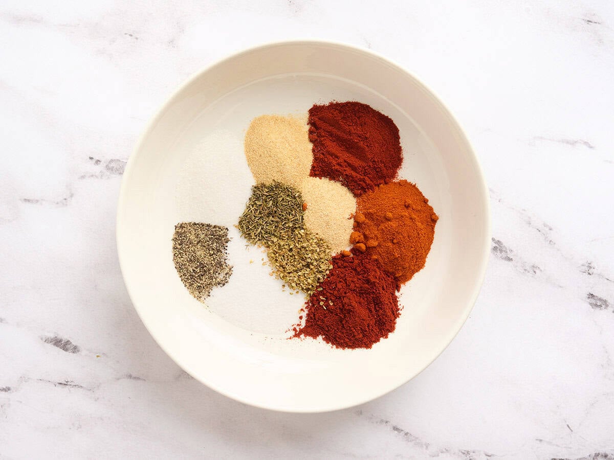 Measured spices for blackened seasoning including paprika, cayenne, garlic powder, onion powder, herbs, salt, and pepper in a bowl