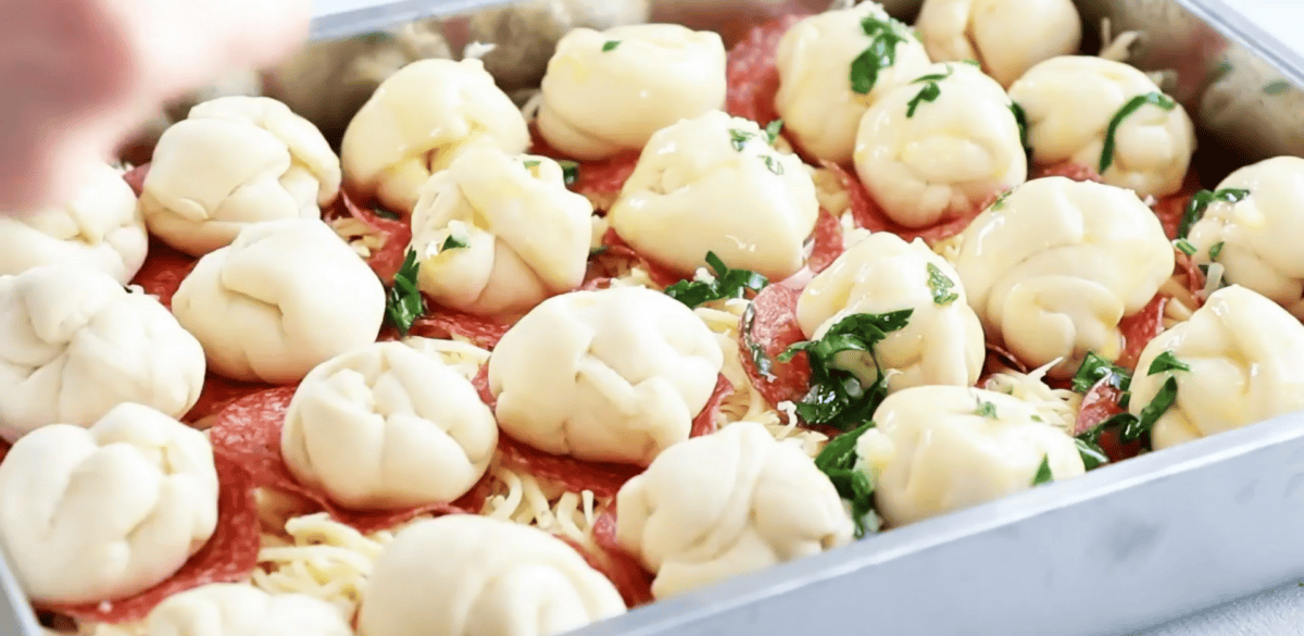dough balls brushed with garlic butter and parsley on top of the unbaked pizza casserole
