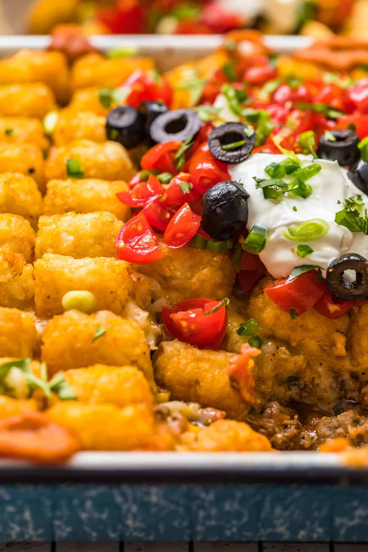 sliced olives and tomatoes on mexican tater tot casserole