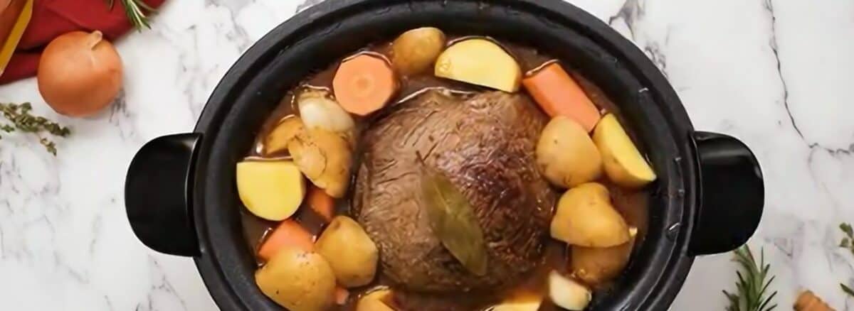Layering vegetables on top of the pot roast.
