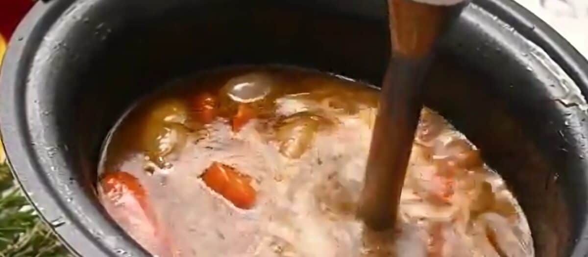 An immersion blender making gravy out of the vegetables and juices in the crockpot. 