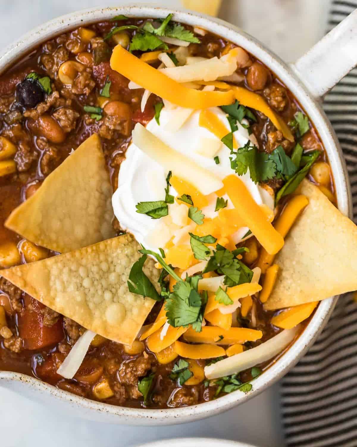 Taco soup in a bowl with sour cream, cilantro, cheese, and tortilla chips.