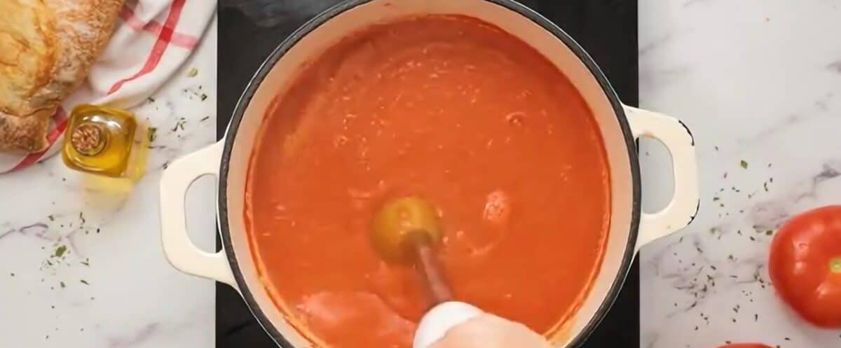 Pureeing tomato soup with a hand blender.
