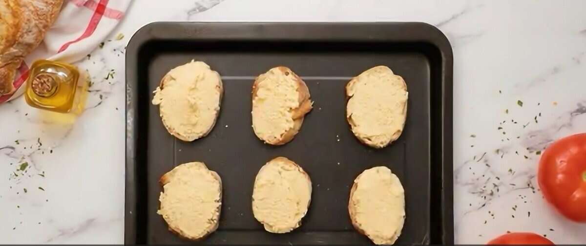 Toasting baguette slices with cheese.