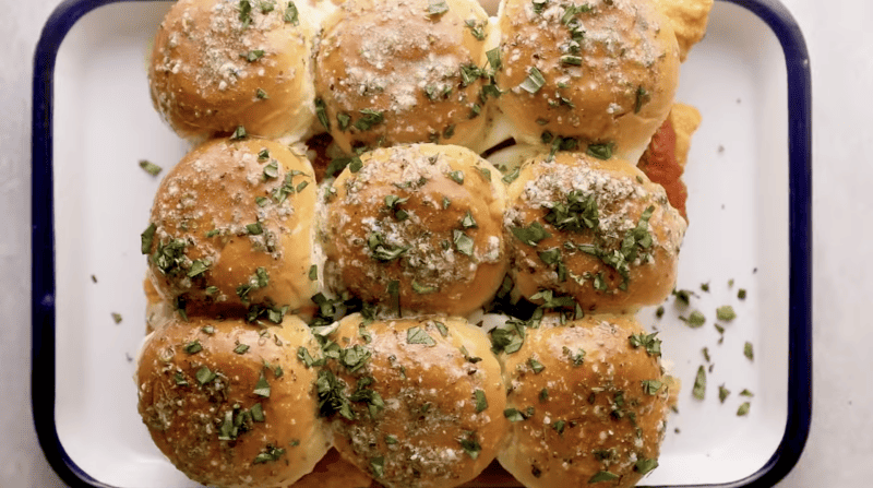 Chicken Parmesan sliders on a plate with parmesan cheese.