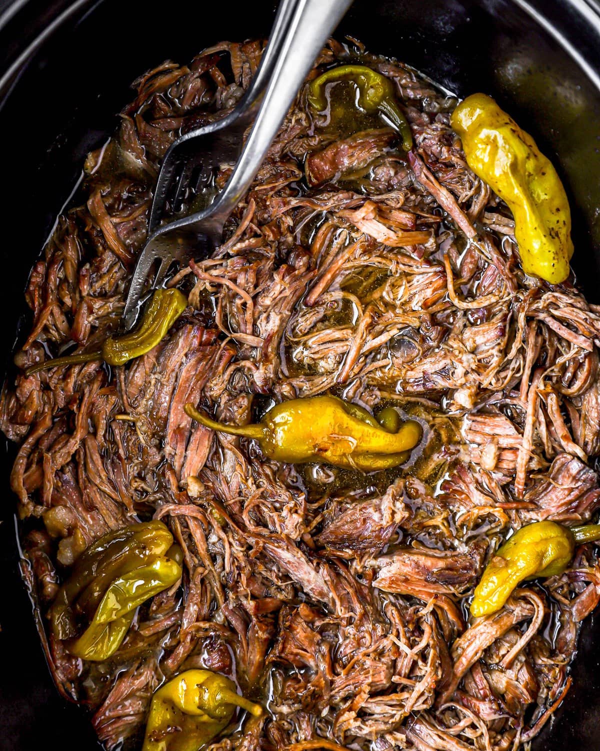 A Mississippi pot roast slow cooker full of meat and peppers.