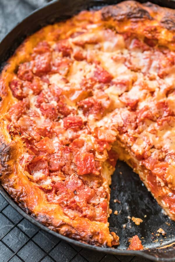 A chicago deep dish pizza with a slice taken out of it