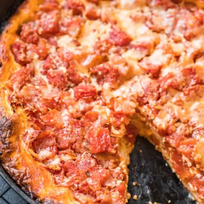 chicago style deep dish pizza in skillet with piece missing