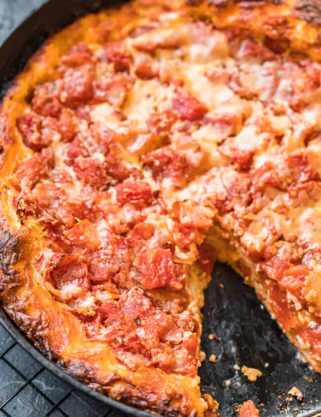chicago style deep dish pizza in skillet with piece missing